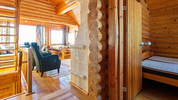 Ein Blockhaus-Interieur mit Essbereich, einer Couch und einem Bett.