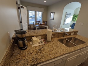 A kitchen with granite countertops, a coffee maker, a sink, and a dining area visible through an open door. - 1 through 2 Bedroom Houses with the best location in Colonial Williamsburg (Williamsburg)