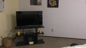 A living room with a flat-screen TV on a black stand, a white fluffy rug, and wall art including a flower and a motivational quote. - Cozy, Clean!  Pets Welcome..Close to Walking/Bike Trail (Aberdeen)