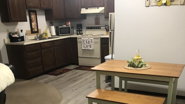 A kitchen with wooden cabinets, a white stove, and a dining table with benches. - Cozy, Clean!  Pets Welcome..Close to Walking/Bike Trail (Aberdeen)