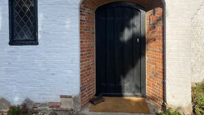 Un edificio bianco con una porta nera e una piccola finestra.