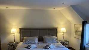 Una camera da letto con un letto grande, due comodini con lampade, una panca ai piedi del letto e un quadro appeso al muro.
