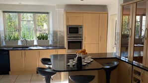 Una cucina moderna con isola centrale, sgabelli da bar, microonde, forno e lavello.