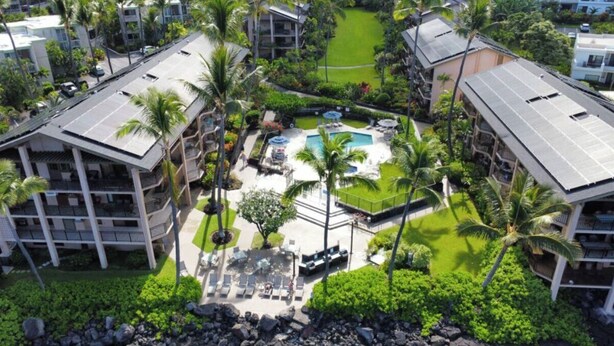 Un resort con piscina central, palmeras y varias edificaciones con balcones.
