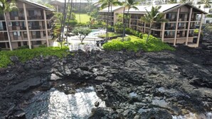 Un hotel con varios pisos, una zona de piscina y abundante vegetación.