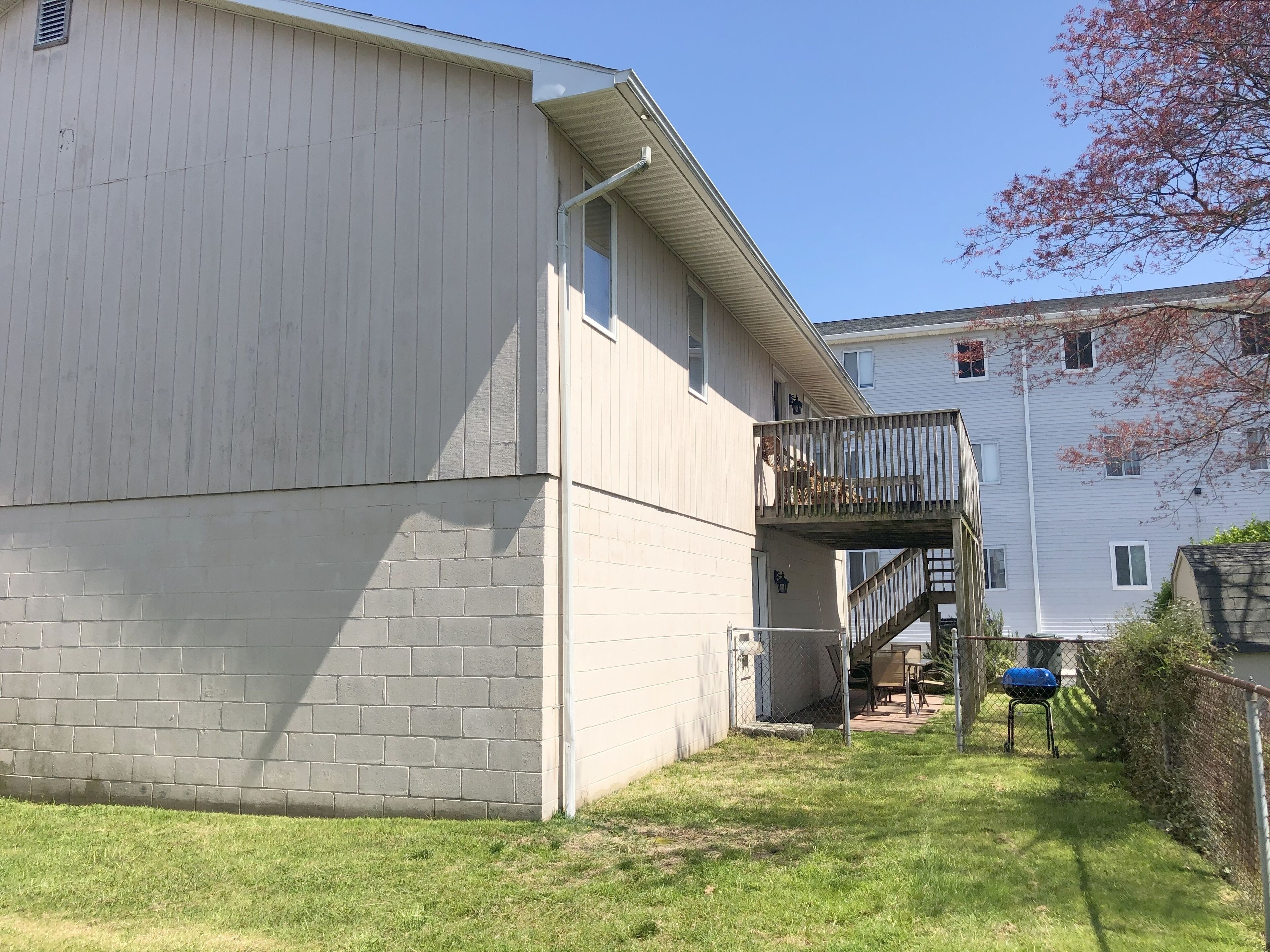 A two-story building with a flat roof, a small deck, and a brick foundation.
