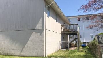 A two-story building with a flat roof, a small deck, and a brick foundation.