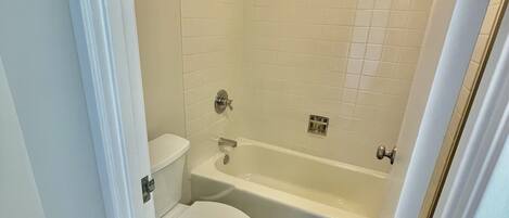 Une salle de bain comprenant des toilettes, une baignoire et une douche.