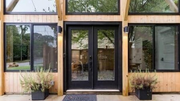 A modern building with a wooden facade, large glass windows, and a black door. - Eva's Zen House | 2BR/2BA | Near Mercedes-Benz (Atlanta)
