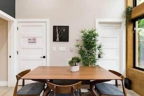 Un comedor con una mesa y sillas de madera, una planta en maceta y una puerta con un cartel de 'No Entry'.