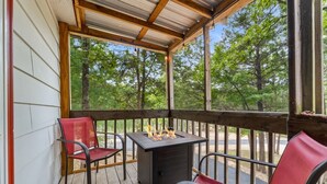 A covered outdoor deck with a metal table and chairs, surrounded by trees. - SADIE'S COTTAGE - Private Hot Tub and Fire Pit (Branson)
