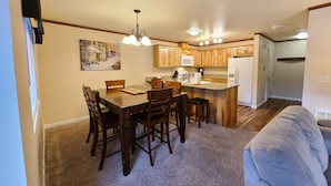 A compact kitchen with wooden cabinets, a dining table with chairs, a built-in island, and a ceiling fan. - The Perfect Place (Leavenworth)