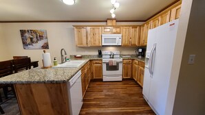 A kitchen with wooden cabinets, a granite countertop, a built-in oven, a microwave, and a refrigerator. - The Perfect Place (Leavenworth)