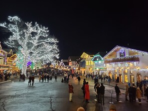 Een levendig plein met verlichte gebouwen en een grote boom versierd met lichtjes.