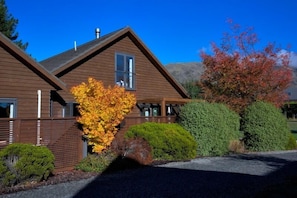 A two-story wooden house with a sloped roof, a visible chimney, and a window with bars. - Heritage Villa 10 (Wanaka)