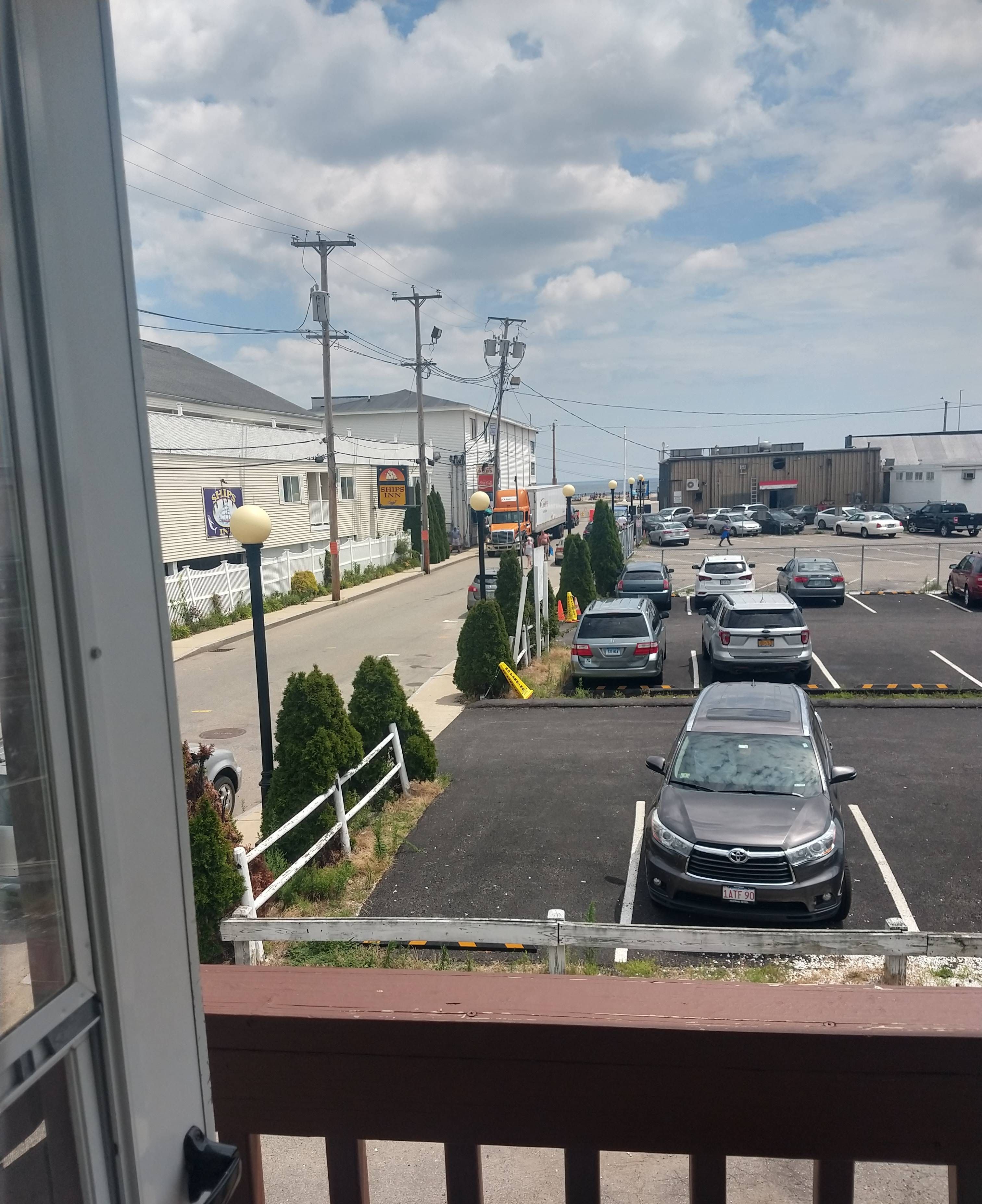 A parking lot with several cars, a building with a sign for 'Shops Inn', and a large truck.