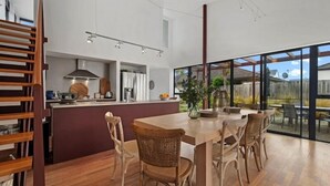 A modern kitchen with a central island, wooden chairs, and a dining table.