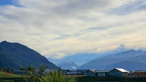 Un paysage montagneux, avec un ciel dégagé et quelques bâtiments au premier plan.
