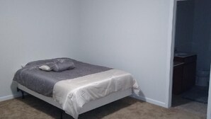 A bedroom with a single bed, a carpeted floor, and a ceiling light.