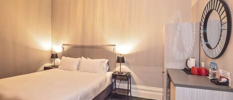 Une chambre d’hôtel équipée d’un lit, de lampes de chevet, d’un bureau avec un miroir et d’une machine à café.