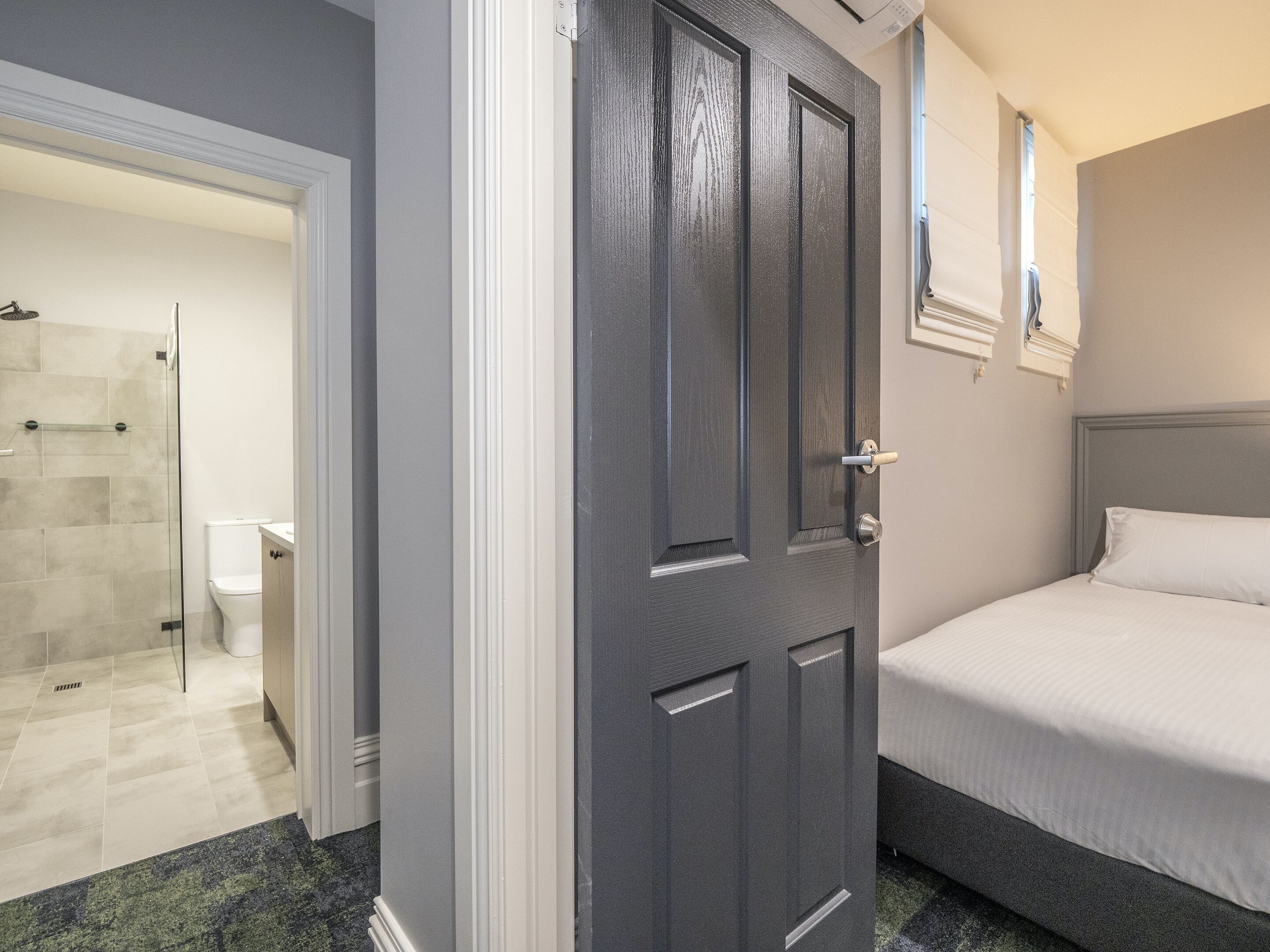 Une chambre à coucher avec un lit, une porte et un espace douche.