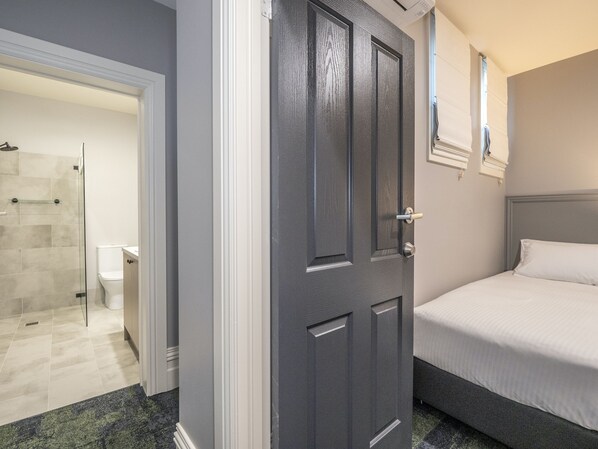 A bedroom with a bed, a door, and a shower area. - Telegraph Hotel Numurkah (Numurkah)