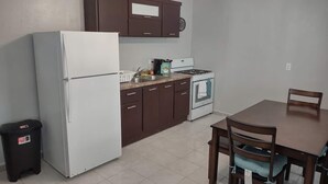A compact kitchen with a refrigerator, stove, and dining table. - The Green House in Vega Alta, Zen zone close to the beach (Vega Alta)