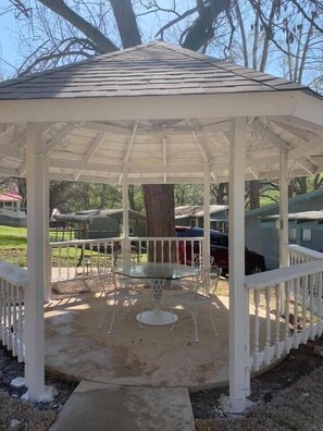 A gazebo with a glass table and chairs, surrounded by a white railing. - River View Retreat LLC (New Braunfels)