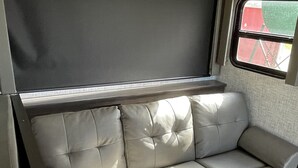 Un canapé gris doté d’un dossier et d’accoudoirs rembourrés, placé contre un mur orné de carreaux aux motifs géométriques.