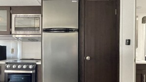 Une cuisine compacte équipée d’un réfrigérateur, d’un four et d’un four à micro-ondes intégrés.
