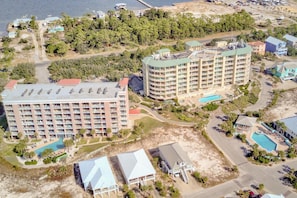 Un hotel moderno de gran altura con varios balcones, una piscina y una zona de playa.