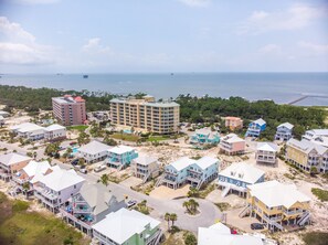 A coastal resort with multiple beachfront buildings, a central hotel, and a pier extending into the water.