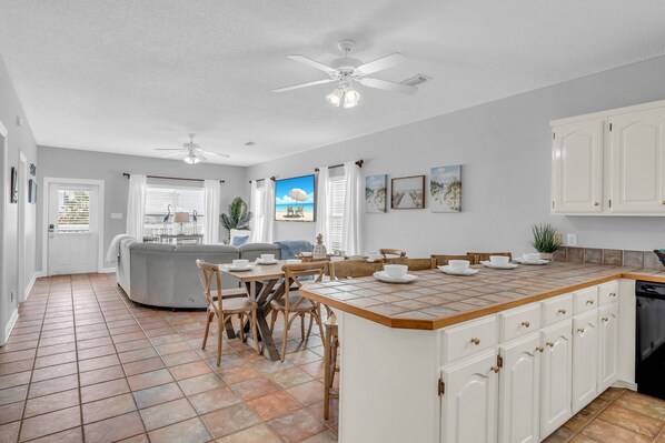 A spacious kitchen with a central island, white cabinetry, and a tiled floor.