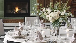 Un coin repas agrémenté d’une cheminée, de tables soigneusement dressées et d’un arrangement floral en guise de centre de table.