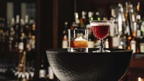 Un coin bar avec un grand saladier à la texture particulière, contenant un cocktail et un verre de whisky.