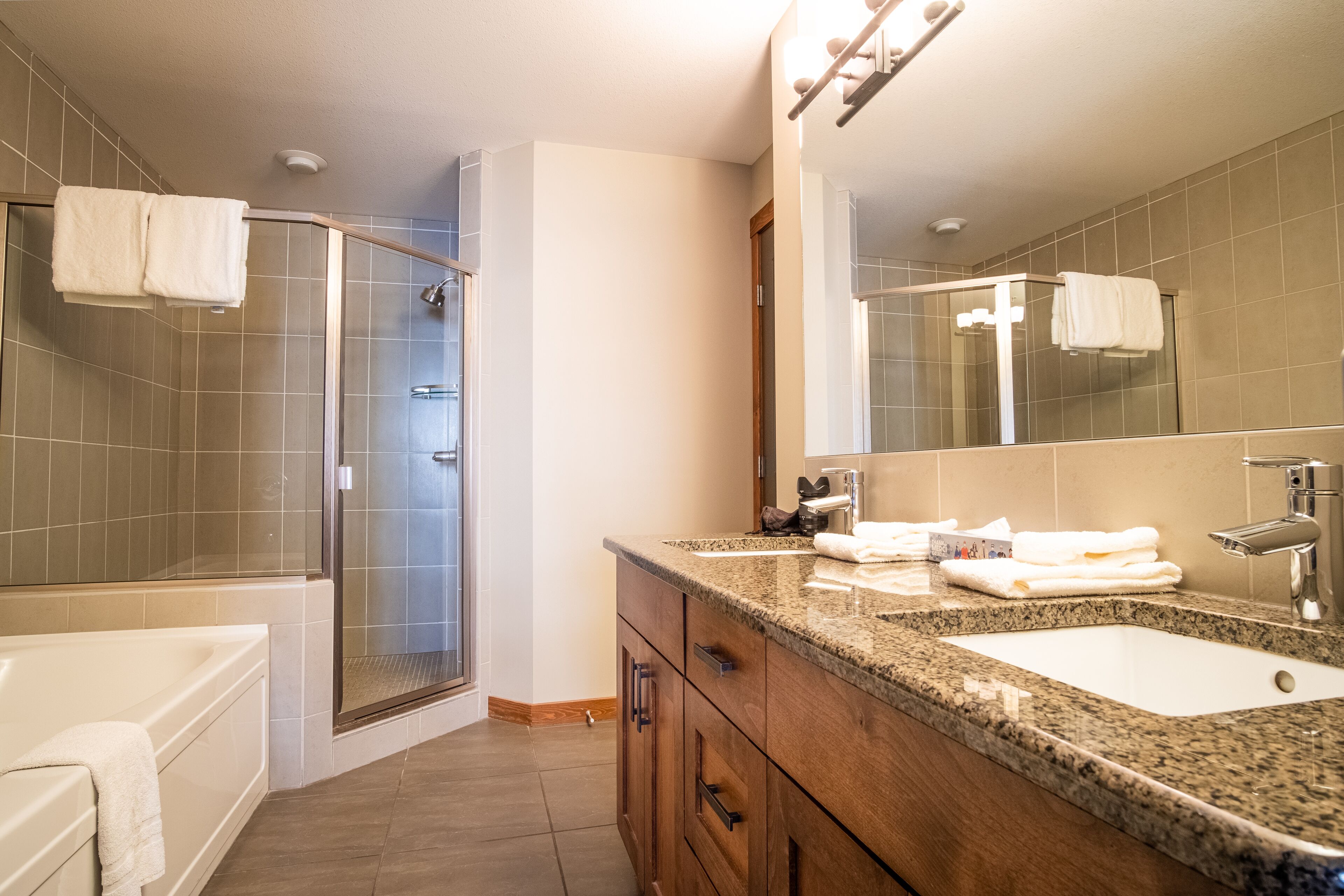 A modern bathroom with a glass shower enclosure, a large mirror, and a granite countertop.