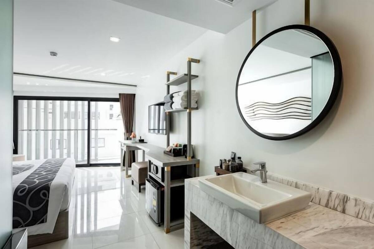 A modern hotel bathroom with a large mirror, a marble sink, and a vanity.
