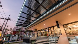 Een modern gebouw met een glazen gevel, een trap die naar een hoger niveau leidt, en een kerstboom op de voorgrond.