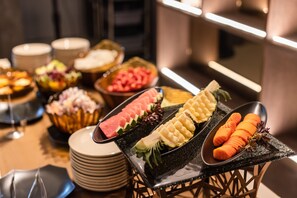Un bufé con diversos platos, incluyendo sandía, queso y rodajas de zanahoria.