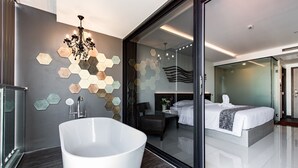 Een moderne badkamer met een vrijstaand bad, een douchecabine met glazen wanden en een wandbekleding van hexagontegels.