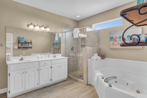 Une salle de bain moderne dotée d’un meuble-lavabo double, d’une douche à l’italienne, d’une grande baignoire et d’un luminaire encastré au plafond.