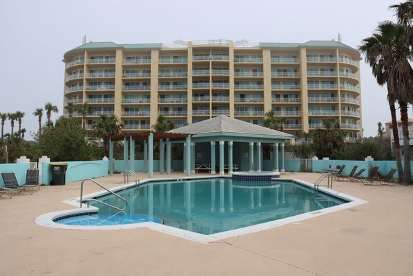 A hotel with a large pool area, including a hot tub and lounge chairs.