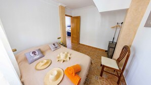 A hotel room with a bed, a chair, a wooden door, and a hallway leading to another room. - Bonita casa en El Perellonet Valencia (Valencia El Perellonet)