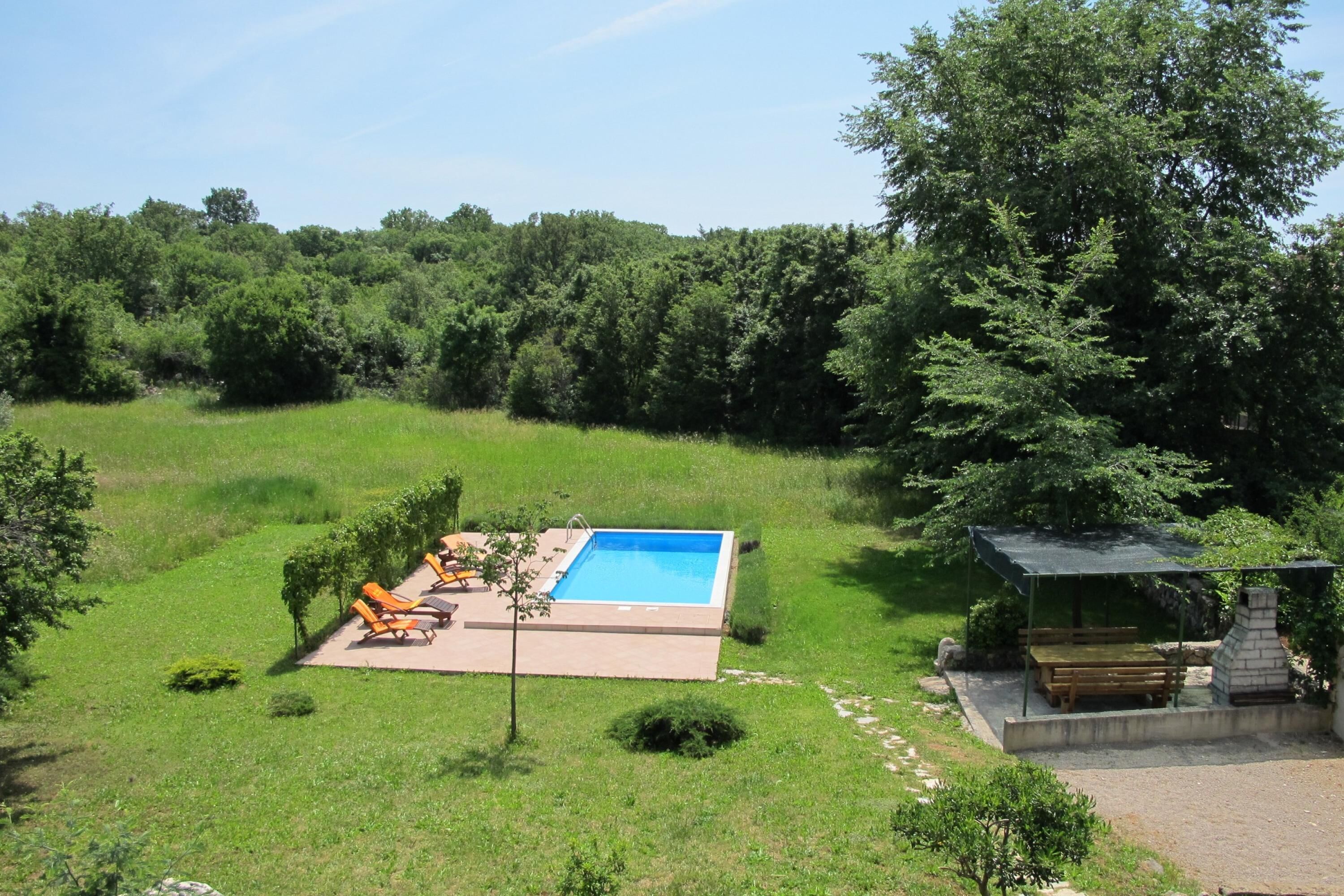 A backyard with a swimming pool, outdoor seating, and a barbecue area.