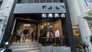 Entrada de un hotel con un cartel que dice "ZINN" y otro cartel en un idioma diferente.