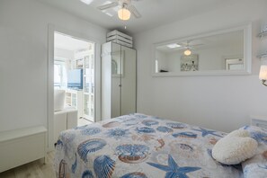 Ein Schlafzimmer mit Bett, Deckenventilator, großem Spiegel und Blick auf einen Balkon.