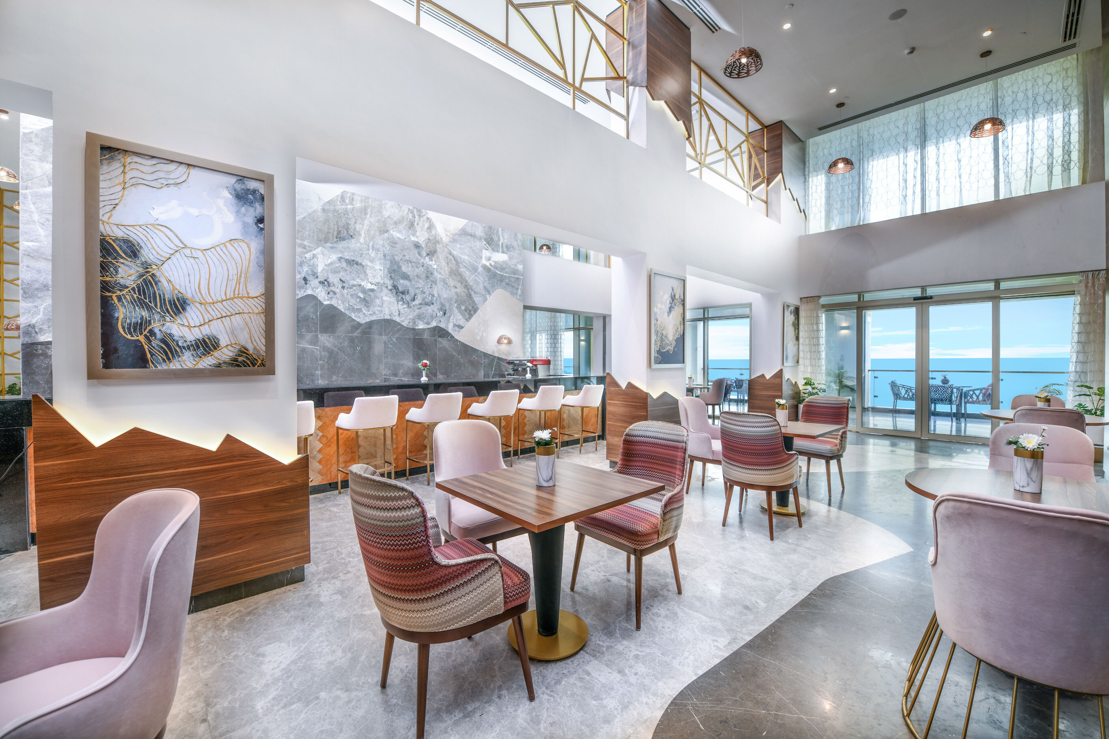 Amplia sala de estar moderna con diversas opciones de asiento, ventanas grandes con vistas al océano y obras de arte contemporáneas en las paredes.