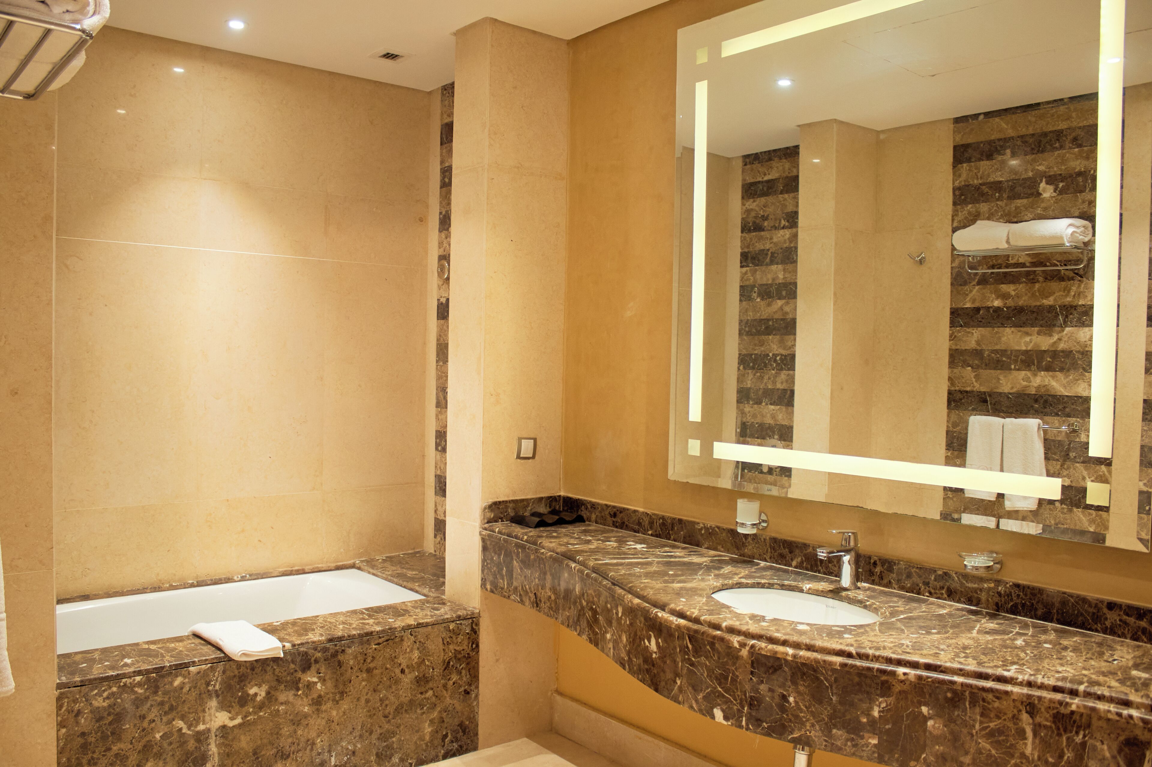 A bathroom with a bathtub, a sink, and a large mirror.