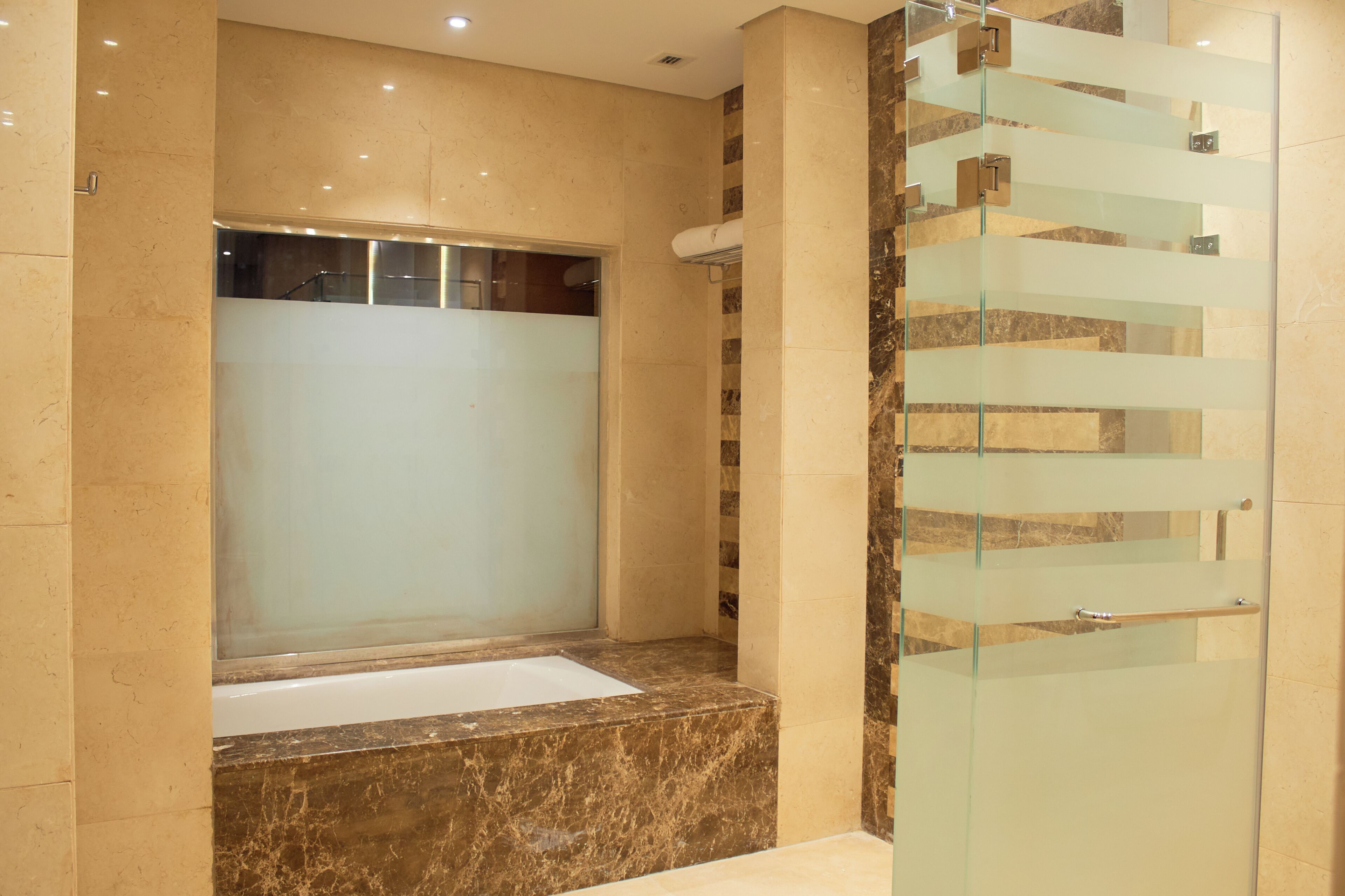Un baño moderno con cabina de ducha de vidrio, suelo de mármol y puerta de cristal.