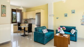Un espacio habitable compacto con kitchenette, una zona de comedor con mesa y sillas, y un conjunto de sofás.